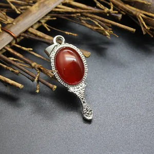 Detailed macro view of vintage hand mirror pendant with an oval red agate stone and floral engraving
