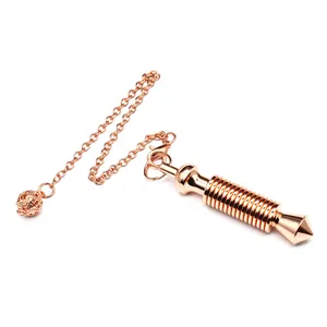 Détail d'un pendule de sourcier en métal or rose avec un cylindre fileté élégant