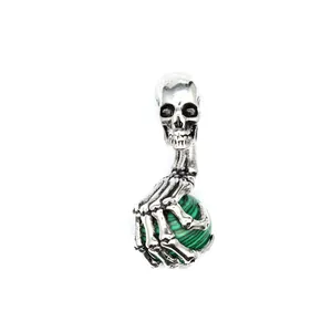 Detailansicht eines gotischen Totenkopf-Anhängers mit Skeletthand und grünem Edelstein