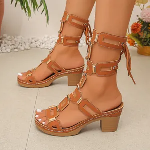 Detailed view of brown hollow-out lace-up sandals with chunky heels and gold accents.