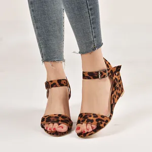 Close-up of women's leopard print wedge sandals with ankle strap buckle and open toe design.