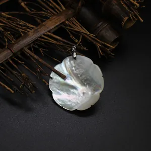 Macro view of a natural mother-of-pearl flower pendant on a Zen bamboo background.