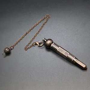 Primer plano detallado de un péndulo hexagonal de metal bronce vintage con cadena.