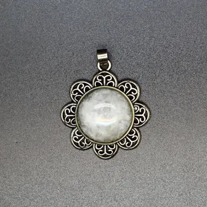 Close-up detail of an antique silver flower pendant with round natural white stone