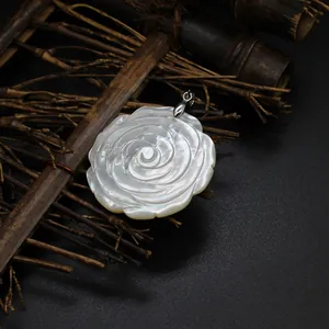 Detail macro shot of a white carved mother-of-pearl rose flower pendant