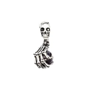 Detailansicht eines silbernen Totenkopf-Anhängers im Punk-Stil mit einer dunklen Perle