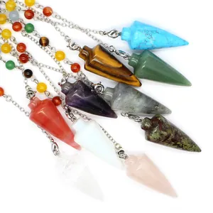 Close-up detail showing various colorful conical crystal dowsing pendulums with chakra beads