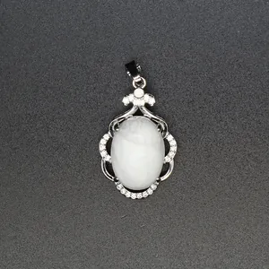 Primer plano de un colgante elegante con piedra blanca ovalada y micro-pavé de cristales