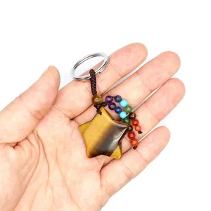 Detailed view of natural tiger eye star keychain with colorful chakra beads held in palm