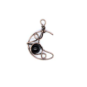 Detail macro view of handmade wire-wrapped crescent moon pendant with black onyx bead