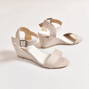 Side view of beige suede wedge sandals with adjustable ankle strap buckle