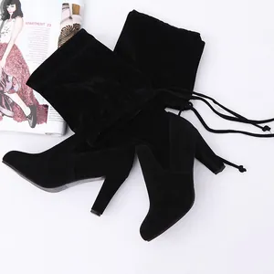 Elegant black suede over-the-knee boots featuring a chunky high heel and lace-up back detail.