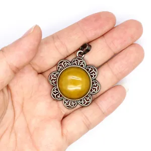 Close-up of antique silver flower pendant featuring a large yellow natural stone in hand.