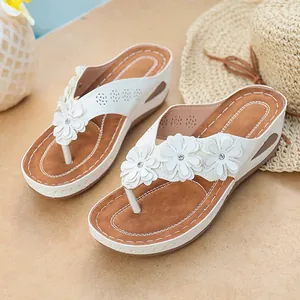 Close-up of white flower thong platform sandals with brown footbed and rhinestone accents
