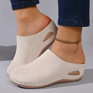 Close-up of beige wedge clogs with decorative stitching and side cutouts for women