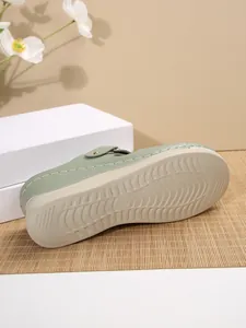 Close-up detail of the durable non-slip sole and white stitching on green wedge sandals