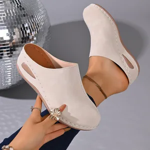 Close-up of beige wedge mules with side cutout and handmade stitching details