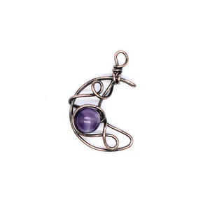 Macro detail view of handmade antique copper wire wrapped crescent moon pendant with purple amethyst