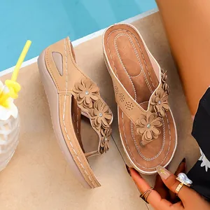 Détail de sandales compensées pour femmes de couleur beige avec fleurs et semelle épaisse.