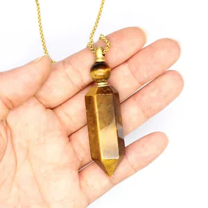 Close-up of a tiger's eye hexagonal aromatherapy bottle pendant on a gold chain