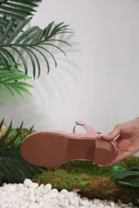 Detailed view of the anti-slip brown sole and pink strap of a women's sandal.