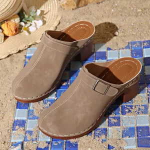 Detail view of khaki closed-toe mules with chunky wooden heels on a beach mat
