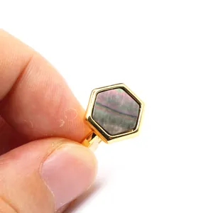 Close-up of a hexagonal natural stone set in a gold-finished open ring.
