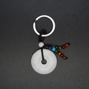 Detailopname van natuursteen donut sleutelhanger met zeven chakra kralen op zwarte basis.