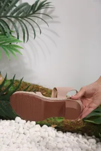 Detailed view of the brown textured non-slip rubber outsole on a women's pink wedge sandal