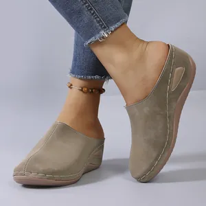 Casual taupe suede-like closed-toe wedge mules with white stitching on model feet