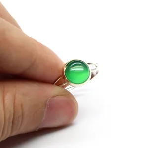 Dettaglio ravvicinato di un anello in argento minimalista con pietra verde tonda.