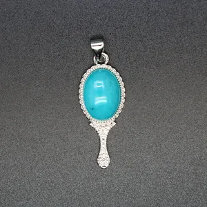 Detailed close-up of a vintage hand mirror shaped pendant featuring a blue turquoise stone