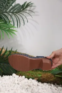 Close-up detail of the durable brown anti-slip sole on stylish blue wedge sandals