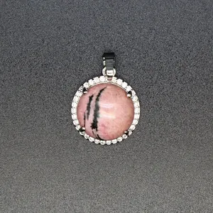 Detaillierte Nahaufnahme eines rosa Natursteinanhängers mit einem Halo aus Kristallen.