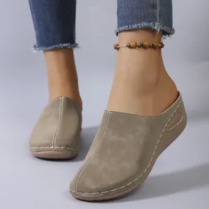 Close-up detail of khaki suede wedge mules with contrast stitching and side cutout.