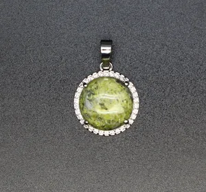 Nahaufnahme eines runden Anhängers aus grünem Naturstein mit glitzerndem Kristall-Halo.