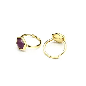 Detailed macro view of two gold-plated open rings with hexagonal purple crystal stones