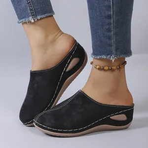 Detailed close-up of women's black wedge mules featuring white stitching and side cutout.