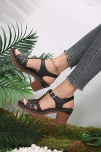 Close-up of black strappy sandals featuring a wooden-style block heel and buckle