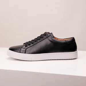 Side view of minimalist black men's leather sneakers with thick white soles