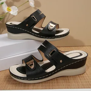 Close-up of black wedge sandals with gold buckles and contrast stitching