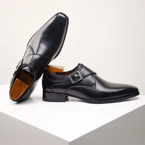 Elegant black leather monk strap shoes with a single buckle on a white display stand