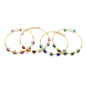 Dettaglio di bracciali intrecciati in oro 14K con varie perle di pietre naturali.