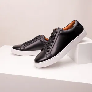 Close-up detail of black leather minimalist sneakers with white soles on geometric props.