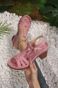 Close-up of pink T-strap sandals with hollow out design and chunky wood grain heels