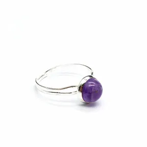 Vista macro di un anello regolabile in argento con una pietra tonda di ametista viola