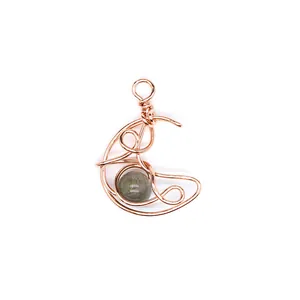 Close-up of handmade rose gold wire-wrapped crescent moon pendant with natural stone