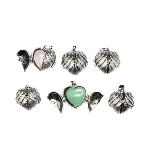 Detailed view of vintage silver angel wing heart locket with natural green stone insert.