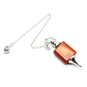 Detailed view of red stone dowsing pendulum with golden Om symbol and silver chain.