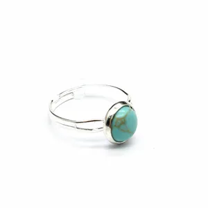 Dettaglio di un anello in argento regolabile con una pietra turchese rotonda centrale.
